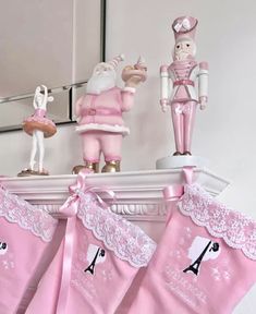 pink stockings hanging from a mantle with figurines on top