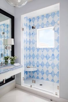 a bathroom with blue and white tile on the walls, shower stall and sink area