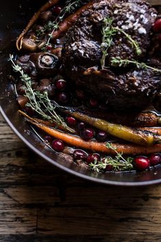 a pan filled with meat and vegetables on top of a wooden table