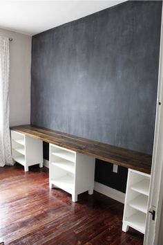 an empty room with two white shelves and a chalkboard on the wall