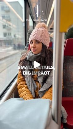 a woman is sitting on the bus and looking out the window with her hat on