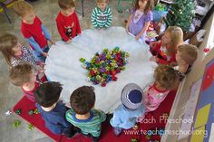 a group of children standing around a table with christmas decorations on it and one boy in the middle