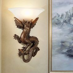 a wall mounted light with a dragon on it's side next to a painting