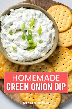 homemade green onion dip in a bowl surrounded by crackers on a wooden platter