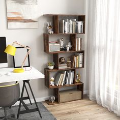 a desk with a computer and bookshelf next to a white curtained window