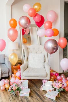 a room filled with balloons and boxes on the floor next to a chair, couch and table