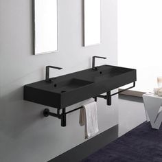 two black sinks in a bathroom with mirrors on the wall and towels hanging from hooks