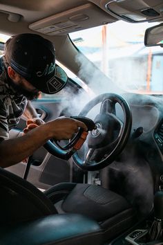 a man driving a car with steam coming out of the air behind his head and steering wheel