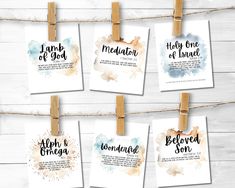 four watercolor wedding signs hanging from clothes pins on a rope with wooden pegs