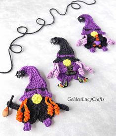 three crocheted witches sitting next to each other on a white surface with a black cord