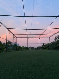 an empty tennis court with the sun setting in the background