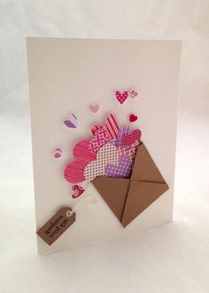 an envelope with hearts and a tag attached to the inside is on a white surface