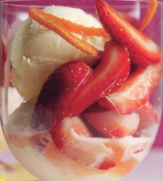 a glass filled with ice cream and strawberries on top of it's side