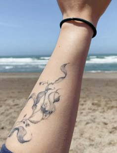 a person's arm with a tattoo on it and the ocean in the background