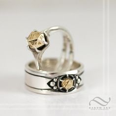 two silver rings with gold hearts on them sitting on top of each other in front of a white background