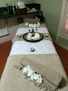 two massage beds with candles and flowers on them