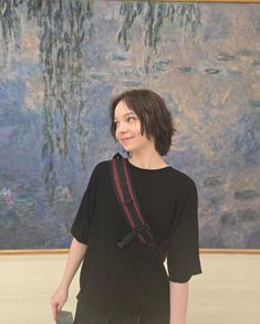 a woman standing in front of a painting with a camera strap around her neck and shoulder