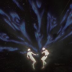 two people standing in the middle of a dark space with bright blue lights on them