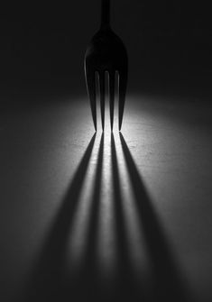 a fork casting a shadow on a table with the light coming through it's back