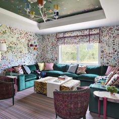 a living room filled with lots of furniture and colorful wallpaper on the walls,