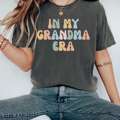 This In My Grandma Era Shirt is the perfect birthday gift, Mother's Day gift, or Christmas gift for your favorite Grandma! All of our shirts are super soft and cozy, and they are made with the highest quality materials! Browse all of our Grandma T-shirts, sweatshirts, Mugs, and tote bags here: https://www.etsy.com/shop/3CShirtDesigns?ref=seller-platform-mcnav&section_id=41809765 PRODUCT DESCRIPTION: ◆   Bella Canvas Unisex T-shirt ◆   100% soft cotton ◆   Light fabric (4.2 oz) ◆   Runs true to s Multicolor Graphic Tee T-shirt As Gift, Cotton Crew Neck T-shirt For Birthday Gift, Multicolor T-shirt For Mother's Day Gift, Funny Graphic Print Tops As Gift, Multicolor Cotton Tops For Birthday, Green Letter Print T-shirt For Birthday, Funny Cotton Tops For Birthday, Fun Crew Neck Top With Name Print, Multicolor Letter Print Shirt For Birthday