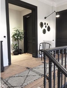 an entry way with black doors and white walls, wood floors and metal railings