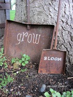 two rusty shovels sitting next to a tree with the word grow written on it