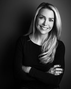 a black and white photo of a woman with long blonde hair smiling at the camera