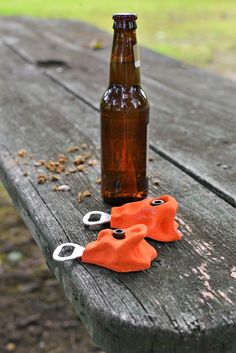 a beer bottle sitting on top of a wooden table next to scissors and an orange cloth