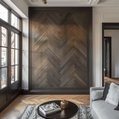 a living room filled with furniture and large windows next to a wooden paneled wall