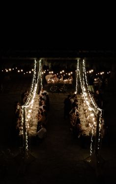 people sitting at tables covered with lights in the dark