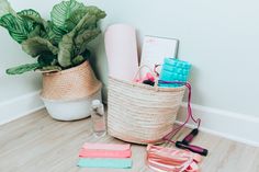 a basket filled with personal care items next to a plant and notebooks on the floor