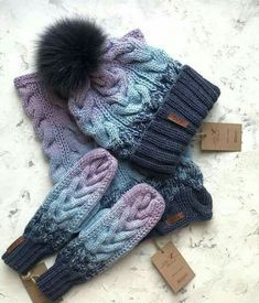 two knitted hats with fur pom - poms on them