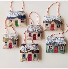 four ornaments are hanging from twine with lace on them, one has a house and the other has a red door