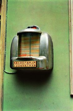 an old radio on the side of a green building with numbers and symbols below it