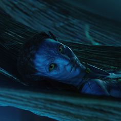 a woman with blue paint on her face and body laying in a hammock