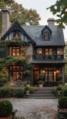 a large house with lots of windows and plants on the front porch, surrounded by greenery