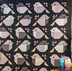 a black quilt with pink and yellow birds on it, sitting next to some crayons