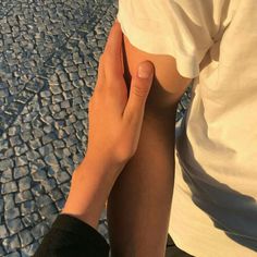 a person with their arm around another persons leg on a cobblestone road in the sun