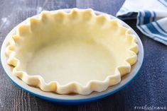 an uncooked pie crust sits on a plate next to a blue and white napkin