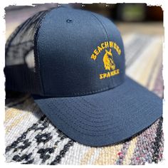 Beachwood Sparks 20th Anniversary Horsey logo embroidered on a dark navy cap with gold stitching...ships from a 3rd party with love. • 60% cotton, 40% polyester • Mid-profile cap with a low-profile embroidery area • Structured, six-panel cap • 3.5″ crown (8.9 cm) • Hard buckram front panels • Mesh back • Permacurv® visor, matching undervisor • Plastic adjustable closure • Head circumference: 21⅝″–23⅝″ (54.9 cm–60 cm) Navy Trucker Hat With Embroidered Logo, Navy Embroidered Logo Trucker Hat, Navy Cap, 3rd Party, 20th Anniversary, Head Circumference, Logo Embroidered, Dark Navy, Low Profile