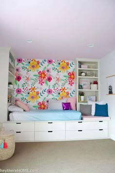 a bedroom with floral wallpaper on the headboard and storage drawers in front of it