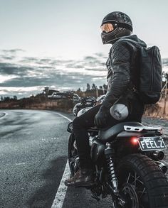 a man riding on the back of a motorcycle down a road