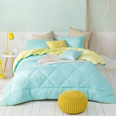 a bed room with a neatly made bed next to a yellow chair and two tables