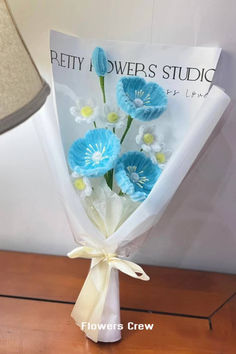 a bouquet of blue and white flowers sitting on top of a table next to a lamp