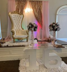 a white chair sitting on top of a wooden floor next to a table covered in flowers