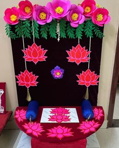 a red table topped with pink flowers on top of a white and black floor next to a wall