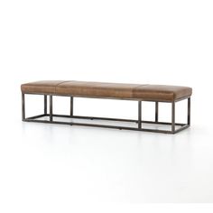 a leather bench sitting on top of a white floor next to a metal frame structure