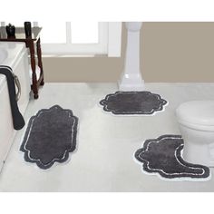 three bathroom rugs on the floor in front of a toilet and bathtub with a sink