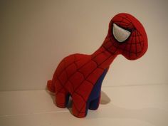 a stuffed toy that looks like a spider - man is sitting on a shelf next to a white wall